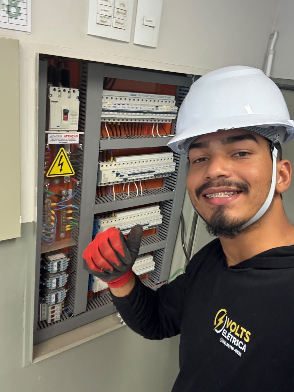 Eletricista da Volts Elétrica com capacete de segurança trabalhando em um quadro elétrico